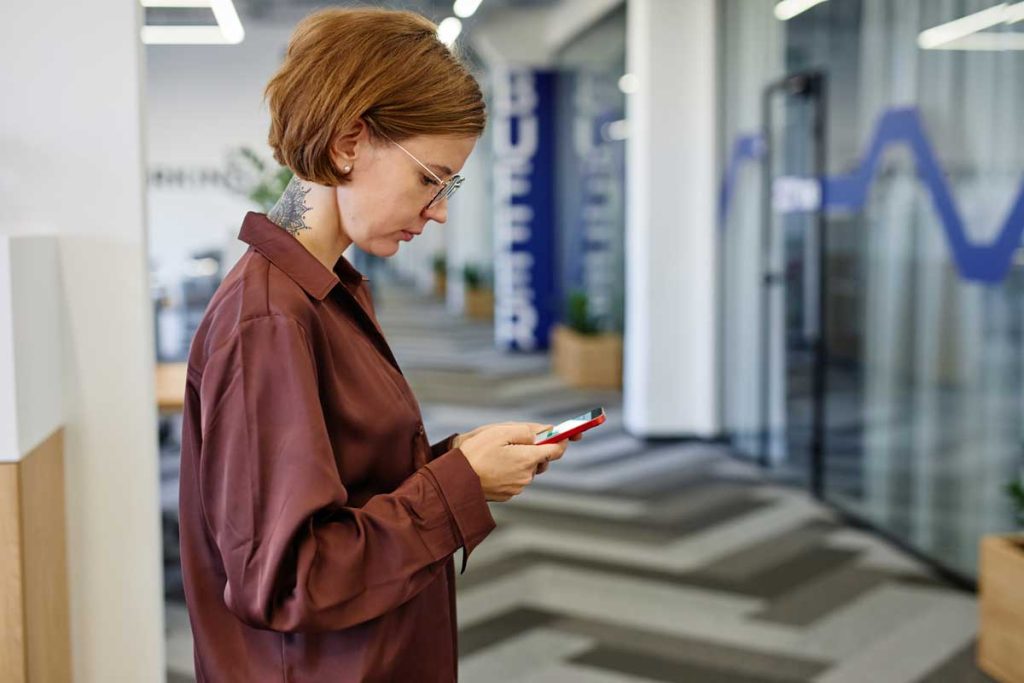 Women in office using a mobile phone to text other people in the office