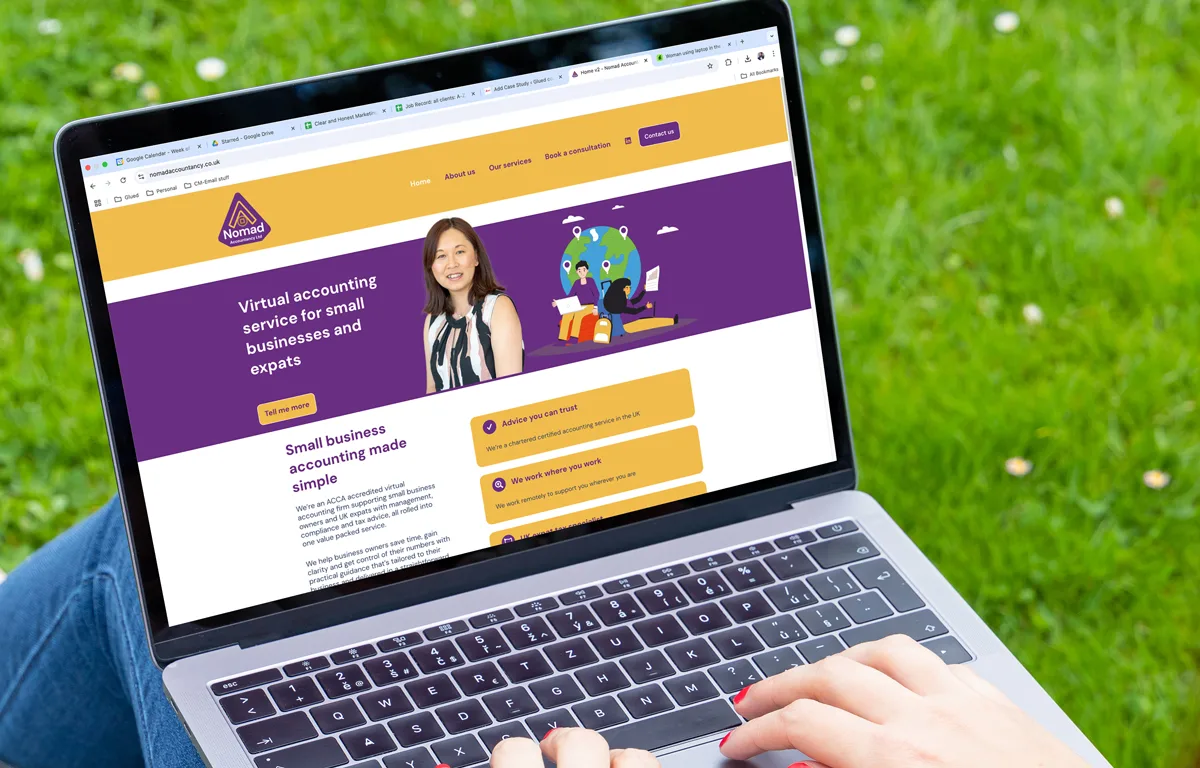 nomad-home A person using a laptop outdoors, displaying the Nomad Accounting website for virtual accounting services tailored to small businesses and expats, with a woman’s photo, a colorful purple and yellow design, and tools for success on the screen.