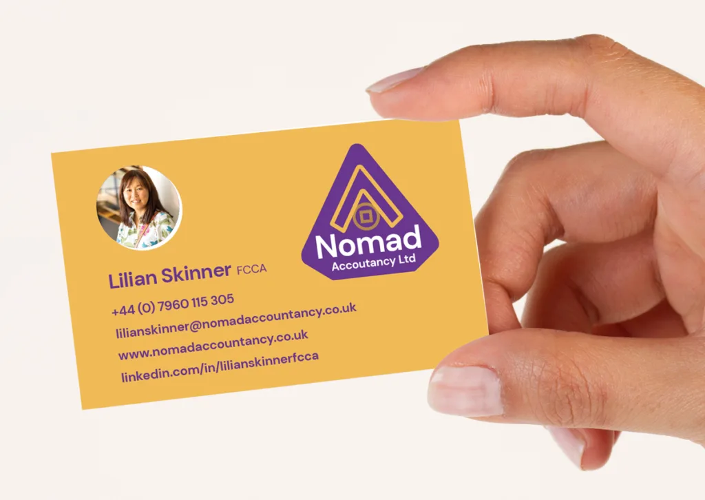 A hand holding a business card for Lilian Skinner at Nomad Accounting Ltd. The orange card features a photo, contact details, and a purple logo with an A and the company name—reflecting professionalism and business success.