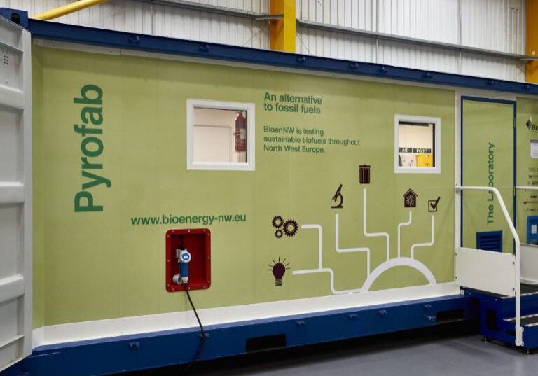 A green and blue modular unit labeled Pyrofab with graphics related to sustainable biofuels stands as a testament to innovative branding by a leading marketing agency in Warwickshire. This initiative promotes an alternative to fossil fuels, focusing on testing sustainable biofuels in North West Europe.