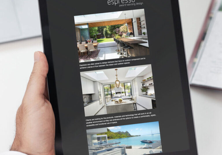 A person holds an iPad displaying a digital magazine titled Espresso, showcasing images of modern interior designs with accompanying text. Nearby, a notebook rests on the table, subtly hinting at Glueds limited edition marketing insights.
