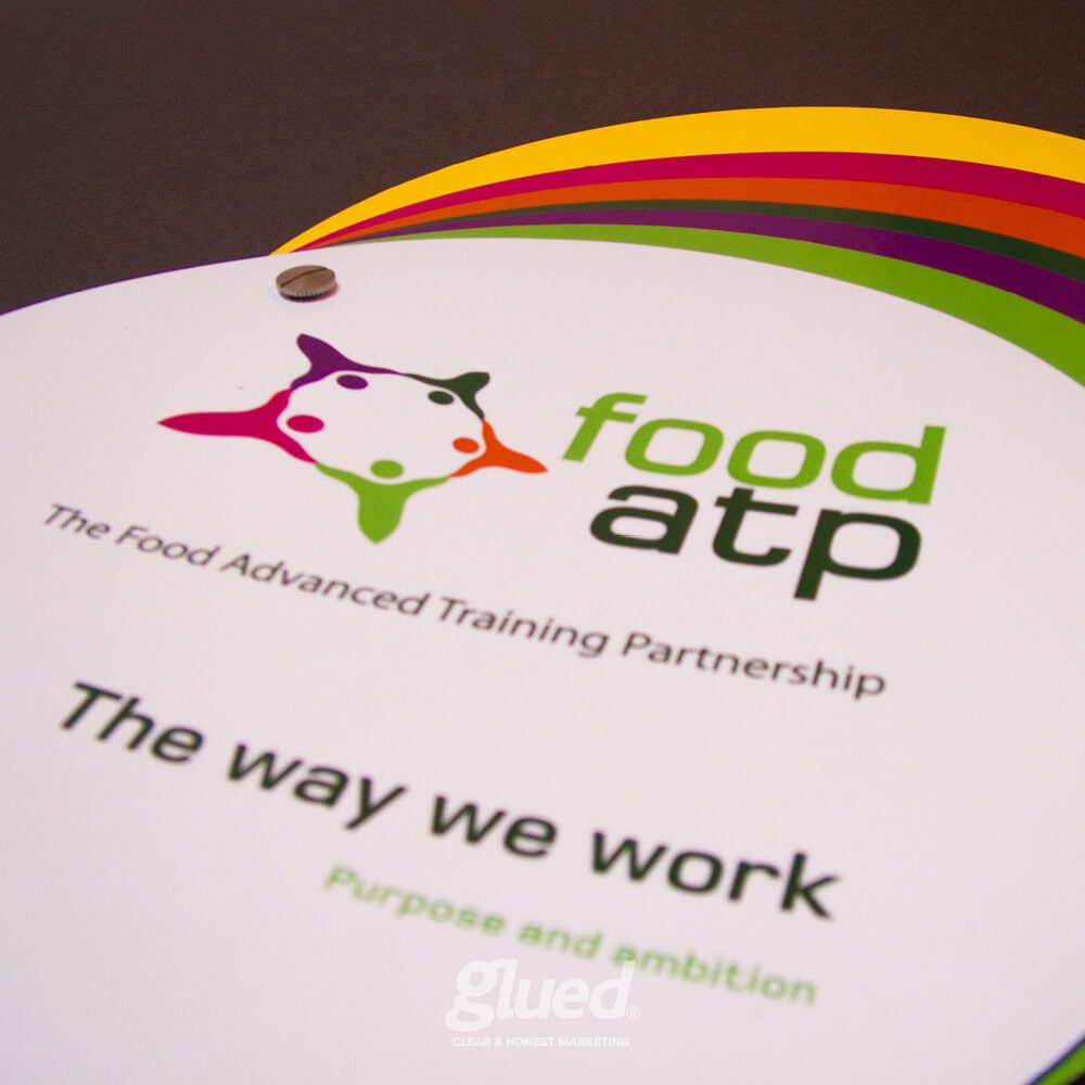 Glued Limited creative work: A close-up of a Food ATP booklet with colourful, overlapping circular tabs and the text “The way we work. Purpose and ambition.” The logo and “The Food Advanced Training Partnership” are visible.