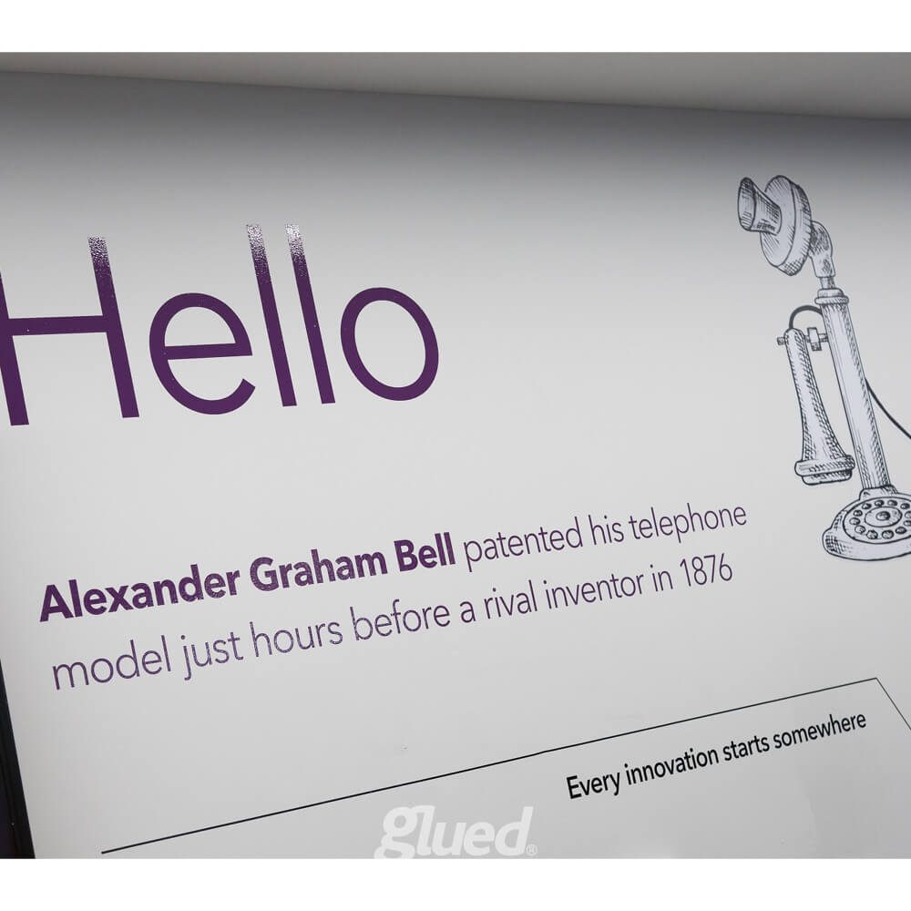 Glued Limited creative work: White sign with large purple text saying “Hello” and a drawing of an old-fashioned telephone. Smaller text reads: Alexander Graham Bell patented his telephone model just hours before a rival inventor in 1876.