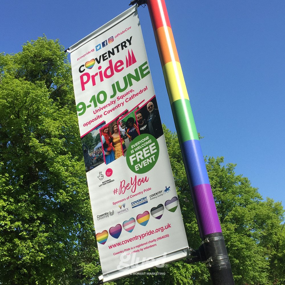 Glued Limited creative work: A vertical banner on a rainbow-striped pole advertises Coventry Pride—an inclusive, free event on 9–10 June at University Square. Rainbow flags and text highlight vibrant marketing campaigns to reach like-minded people across the city.