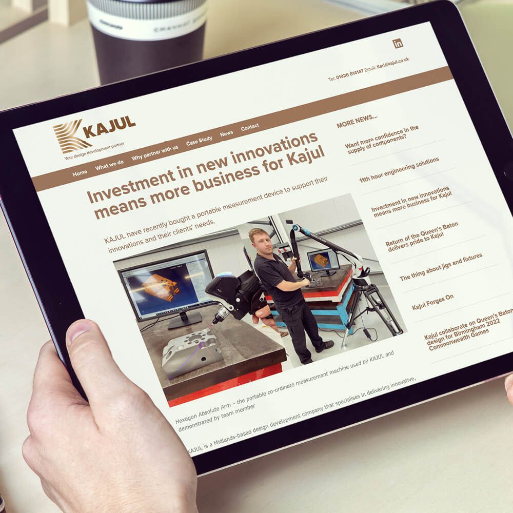 Glued Limited creative work: Person holding a tablet displaying a news article titled “Investment in new innovations means more business for Kajul,” featuring a photo of a man demonstrating equipment beside a screen—highlighting Wordpress website design and build at affordable prices.