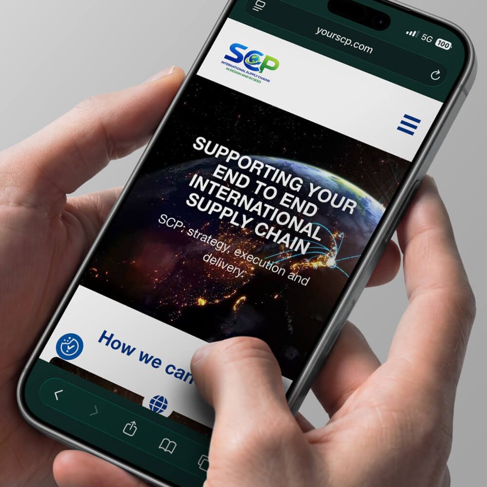 Glued Limited creative work: A person holds a mobile phone displaying a Wordpress website design and build at affordable prices, reading SUPPORTING YOUR END TO END INTERNATIONAL SUPPLY CHAIN over an image of Earth from space, with the SCP logo at the top.