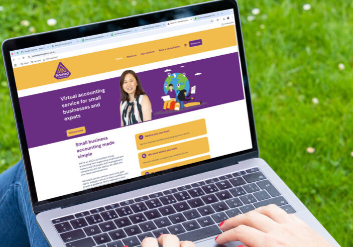A person using a laptop outdoors, displaying the Nomad Accounting website for virtual accounting services tailored to small businesses and expats, with a woman’s photo, a colorful purple and yellow design, and tools for success on the screen.
